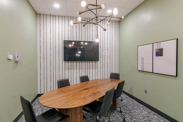 Conference room at Chronicle on 8th with long tables, black chairs, and a presentation screen.